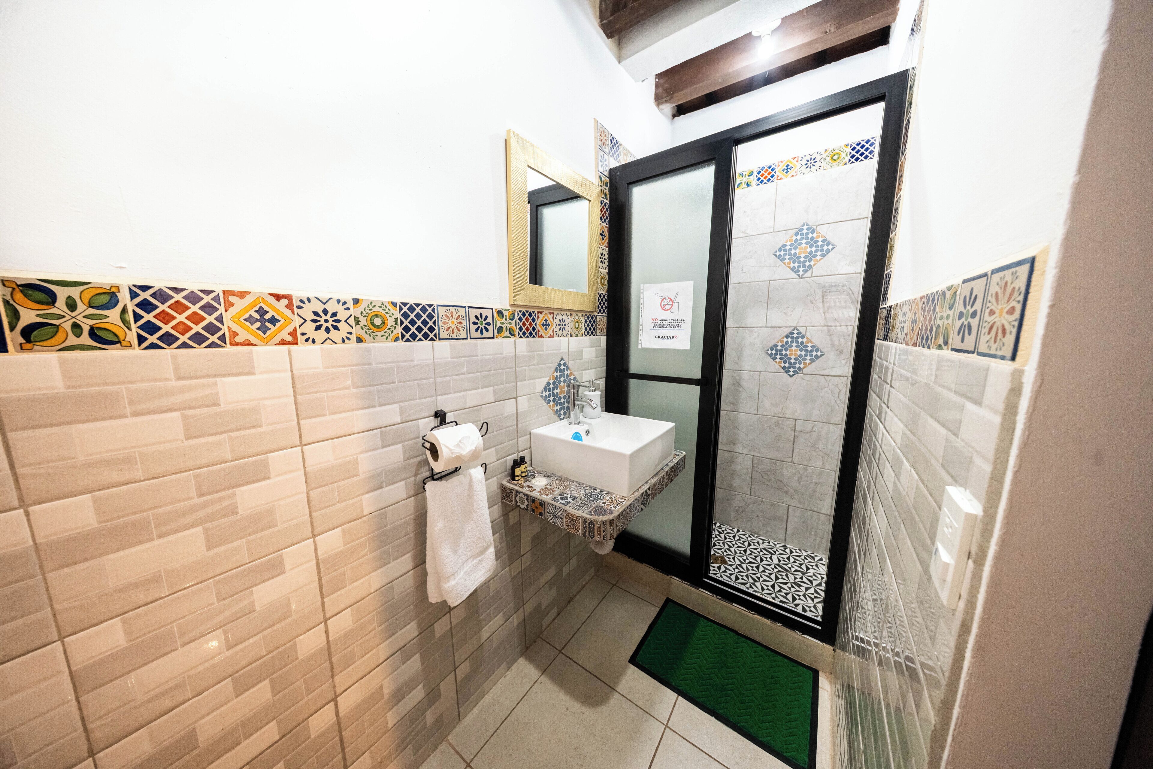 A bathroom with a sink, mirror, and patterned tiles.