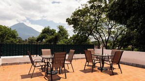 Um terraço com mobiliário ao ar livre, piso de azulejos e vista para uma montanha.