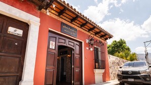 Entrada de um hotel com uma placa indicando 'Los Faroles Hotel & Spa', uma placa de 'proibido estacionar' e um carro estacionado.