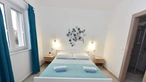 A bedroom with a bed, two bedside tables, a wall decoration, and a window with curtains. - Apartments Ana - Studio apartment (Srima)