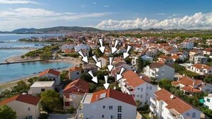 A coastal town with a marina, white buildings with red roofs, and a clear view of the sea and hills in the background. - Apartments Ana - Studio apartment (Srima)