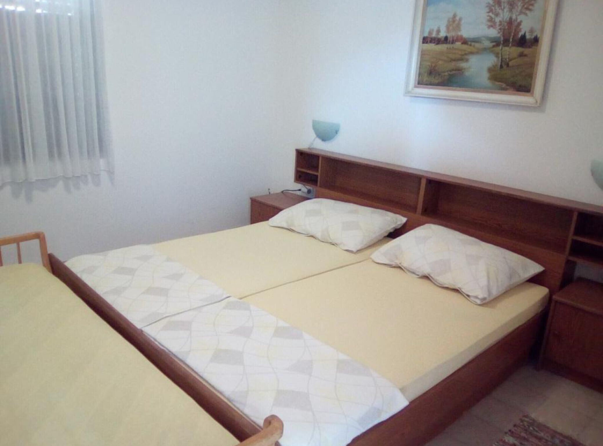 A double bed with a wooden headboard, two bedside tables, and a nightstand.