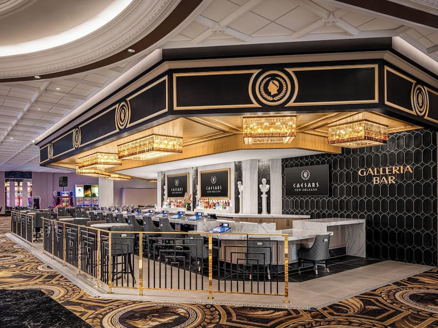 A Galleria Bar, com balcão de mármore, vários bancos e um tapete estampado.