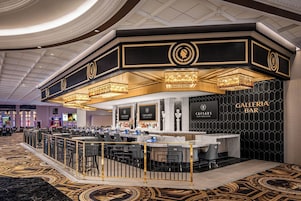 Un bar Galleria con mostrador de mármol, varios taburetes y una alfombra estampada.