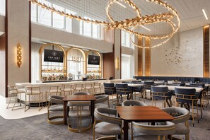 A spacious lounge with multiple seating areas, a bar, and a large decorative light fixture. - Caesars New Orleans - A Caesars Rewards Destination (New Orleans)