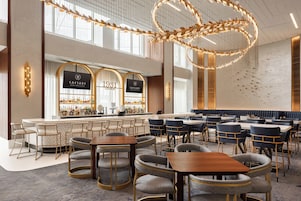 A spacious lounge with multiple seating areas, a bar, and a large decorative light fixture.
