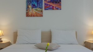 Ein Hotelzimmer mit Bett, weißen Kissen, einer rosa Bettdecke und zwei Bildern an der Wand.