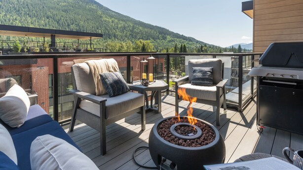 A deck with outdoor seating, a fire pit, and a grill. - Big Hill Penthouse Chalet (Revelstoke)