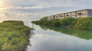 Een gebouw aan het water met een rustige rivier, omringd door groen.