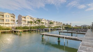 Een hotel aan het water met meerdere balkons, een aanlegsteiger en een helder uitzicht op het water.