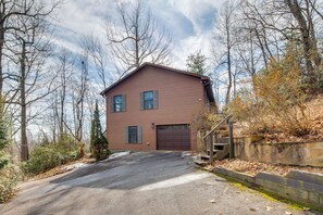 Une maison à deux étages, avec une façade marron, un garage à l’avant et une allée menant à l’entrée.