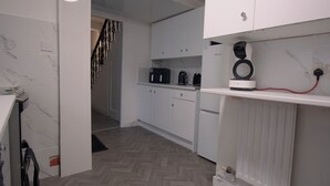 Moderni keittiö, jossa on valkoiset kaapit, sisäänrakennettu uuni ja kahvinkeitin.
