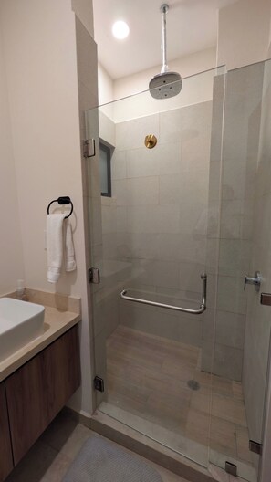 A modern bathroom with a glass shower enclosure, a white sink, and a towel rack. - Vista Cortes 2BR 2BA Condo - Walk to the Malecon! (La Paz)