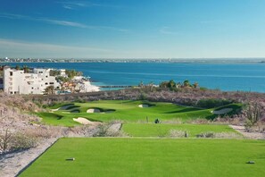 Um campo de golfe com bunkers e vista para o oceano.