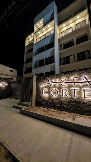 Um edifício com várias andares, fachada de pedra e letreiros iluminados com a inscrição 'VISTA CORTE'.