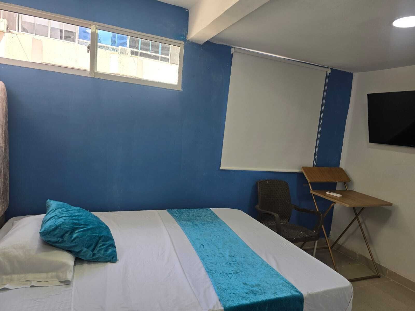Une chambre à coucher avec un lit, une fenêtre, un bureau et une chaise.