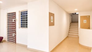 A hallway with a staircase, a door with a sign, and a window with a grid pattern. - Edificio Los Manglares  (Cartagena)