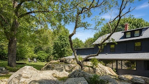 A house with a stone foundation, large rocks, and a tree in the foreground. - Stay at Good Harbor Beach (Gloucester)