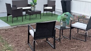 An outdoor patio with wicker furniture, a small table, and potted plants. - Charming Little Nook Near Universal Parks & Outlets. (Orlando)