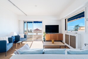 A modern hotel room with a sofa, a TV, a coffee table, and a view of the sea. - Marius By Terry's Homes (Cannes)