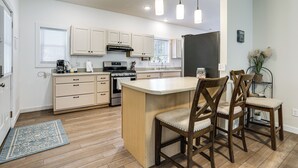 Una cucina moderna con mobili bianchi, un'isola centrale e sedie in legno.