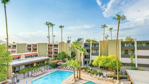 Et hotelområde med swimmingpool, liggestole, palmer og en bygning med altaner.