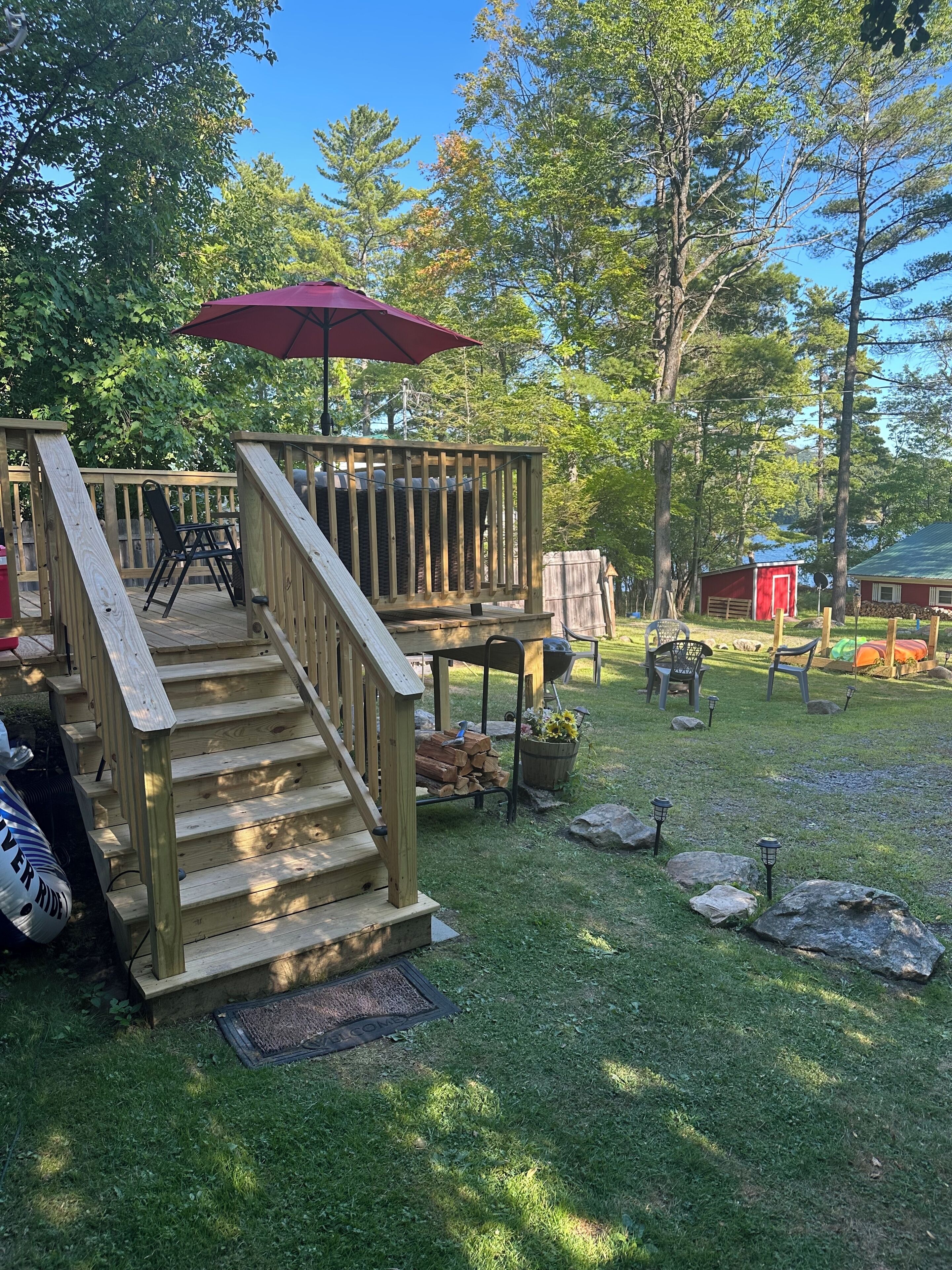 A wooden deck with a staircase, outdoor furniture, and a red umbrella.