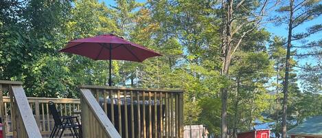A wooden deck with a staircase, outdoor furniture, and a red umbrella.