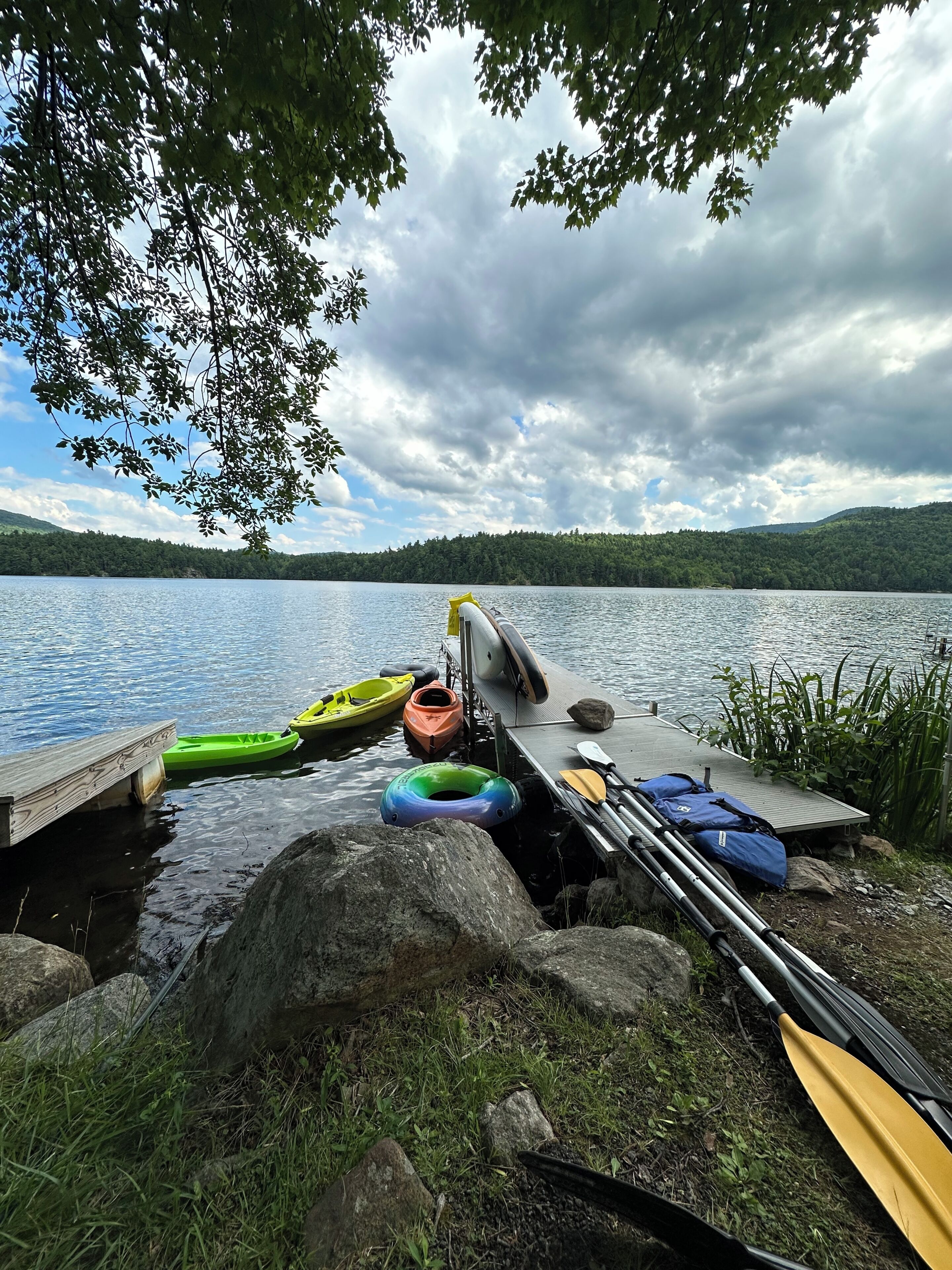 Une jetée au bord du lac avec des kayaks, une pagaie et un bateau.
