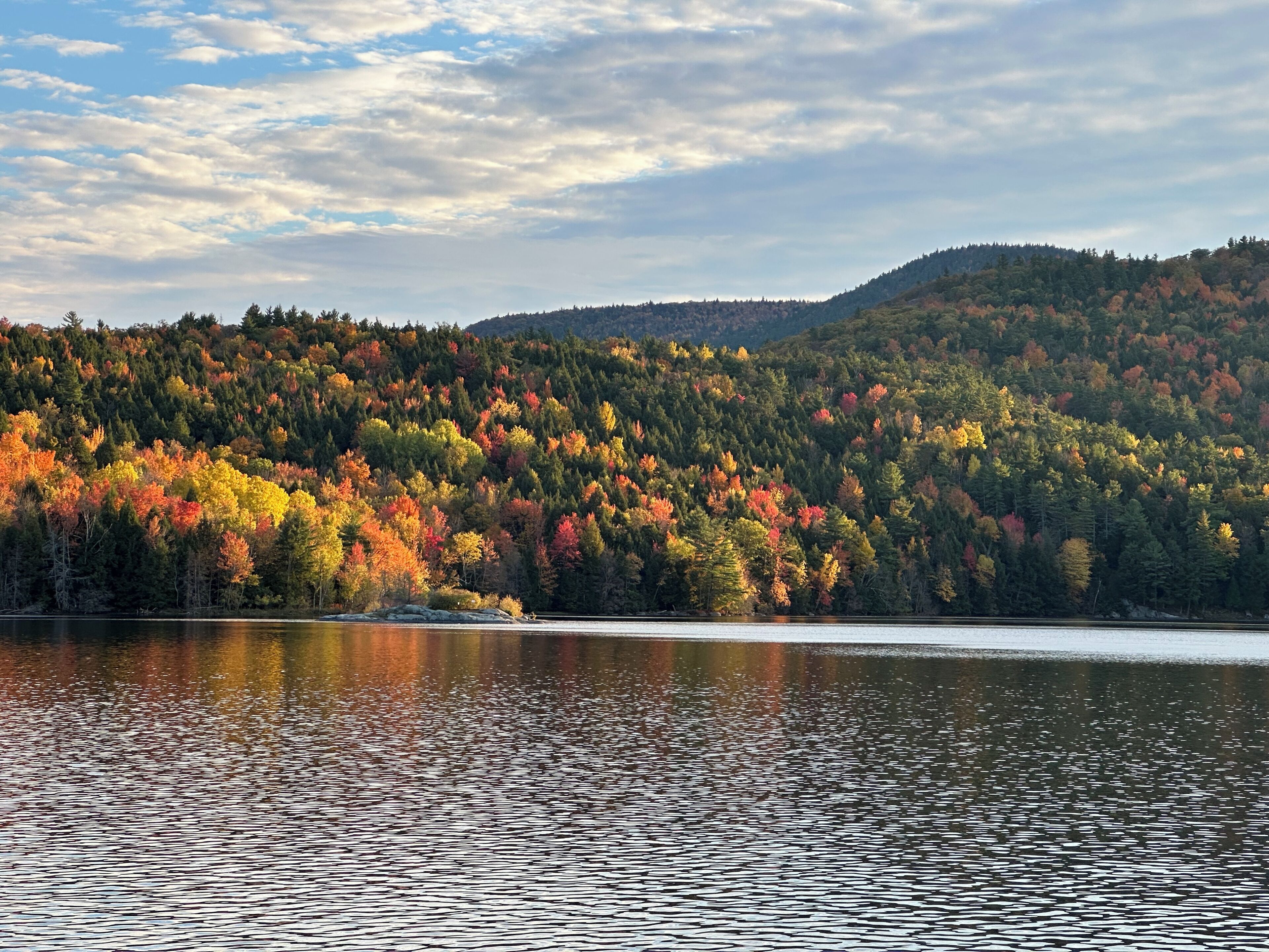Ein See, umgeben von einem Wald mit Herbstlaub.