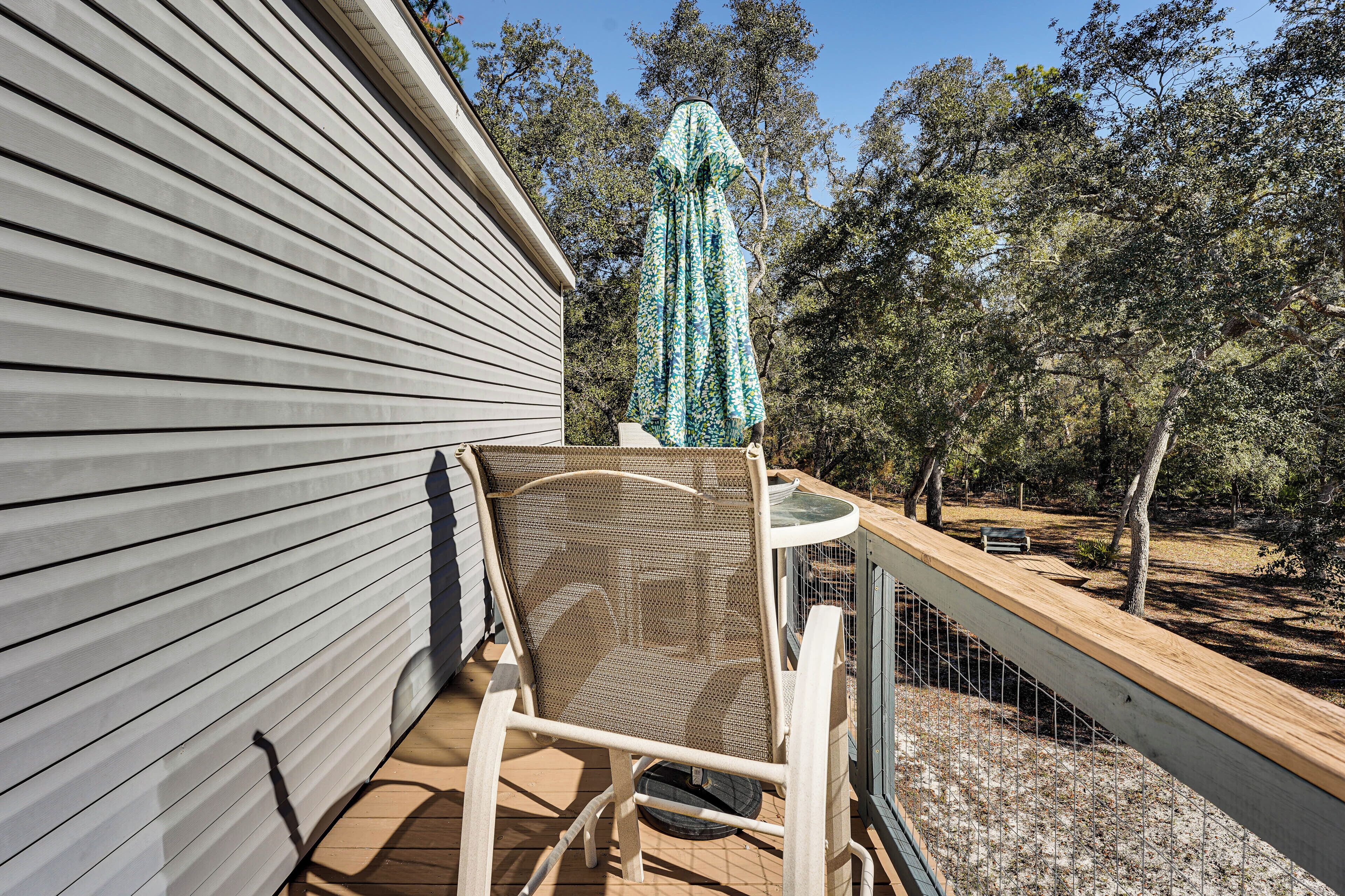 A patio with a wicker chair, a small table, and a blue patterned umbrella.