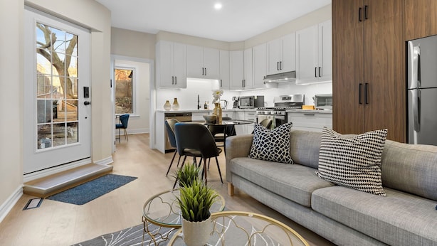 A modern kitchen with white cabinets, a built-in oven, and a refrigerator. There is a dining area with a table and chairs. - Modern Styled 2B/2B, Full kitchen, Laundry, Parking (paid) (Toronto)