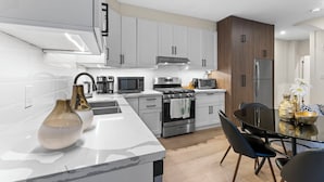 A modern kitchen with white cabinets, stainless steel appliances, and a marble countertop. - Modern Styled 2B/2B, Full kitchen, Laundry, Parking (paid) (Toronto)