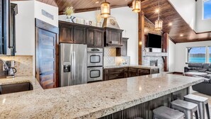 A modern kitchen with granite countertops, stainless steel appliances, and a large island with bar stools. - Comfort, Convenience, and Room for the Whole Crew (Garden City)