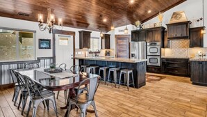 A spacious kitchen with a central island, dark cabinetry, and a wooden ceiling. - Comfort, Convenience, and Room for the Whole Crew (Garden City)