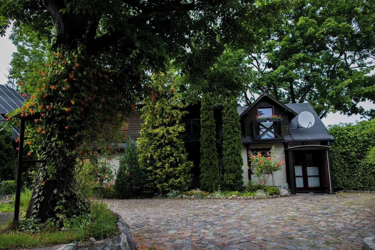 Una casa tradicional con entrada de piedra, rodeada de abundante vegetación y árboles.