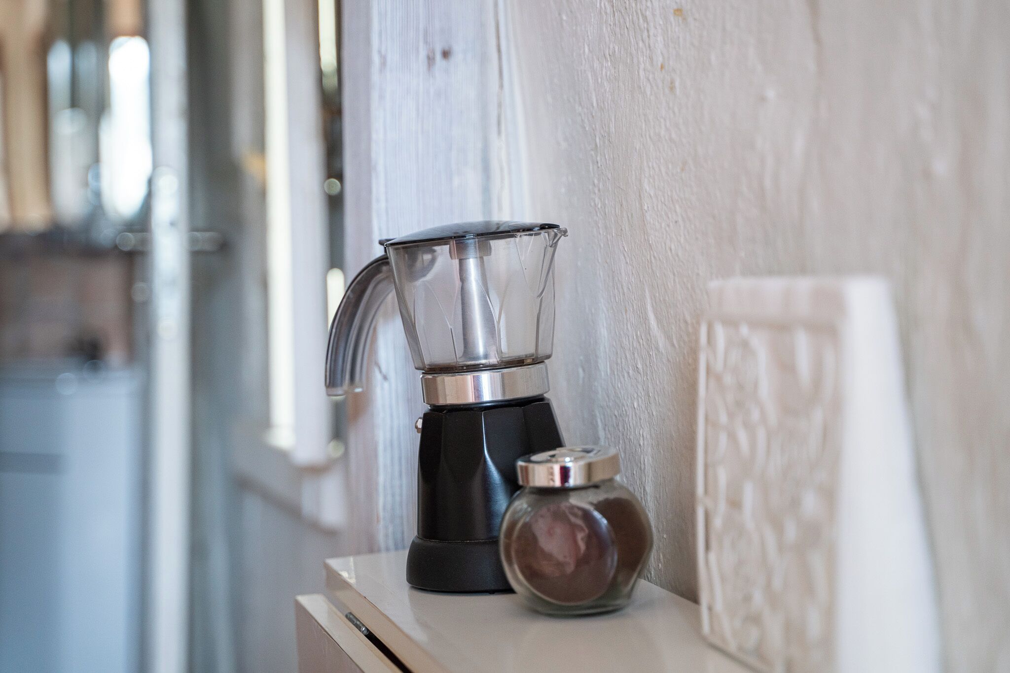 A kitchen with a coffee maker and a spice jar on a counter.