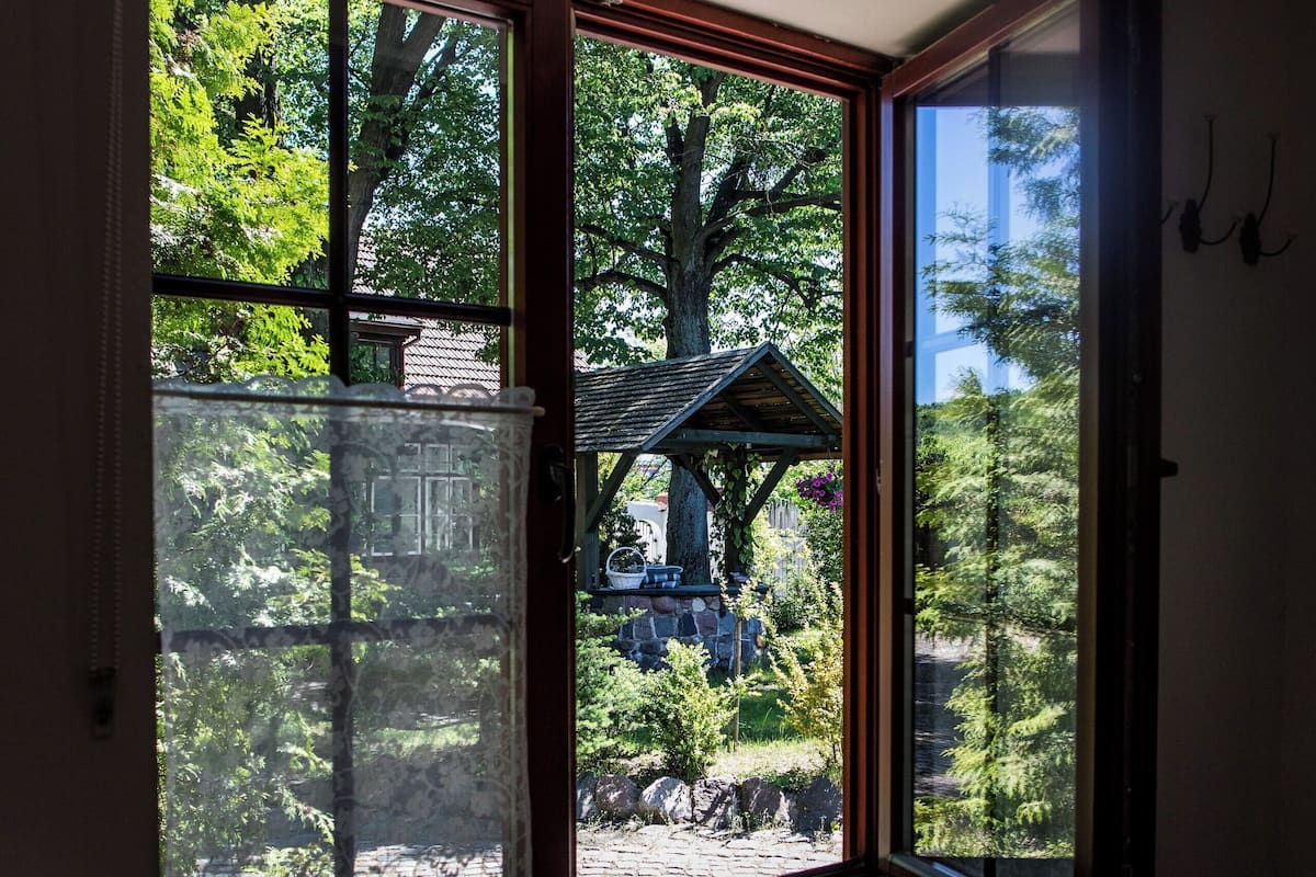 Una habitación con un gran ventanal que da a un jardín con una estructura de madera y árboles.