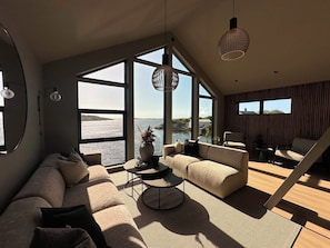 A modern living room with a large window, a sofa, a coffee table, and a chair.