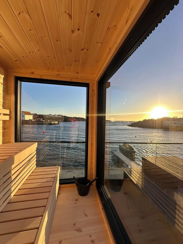 A wooden cabin with a large window overlooking a body of water.