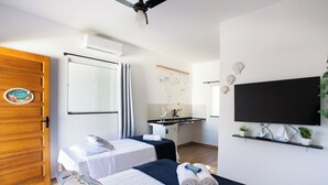 Une chambre d’hôtel avec un lit, un bureau, une télévision et une petite plante.