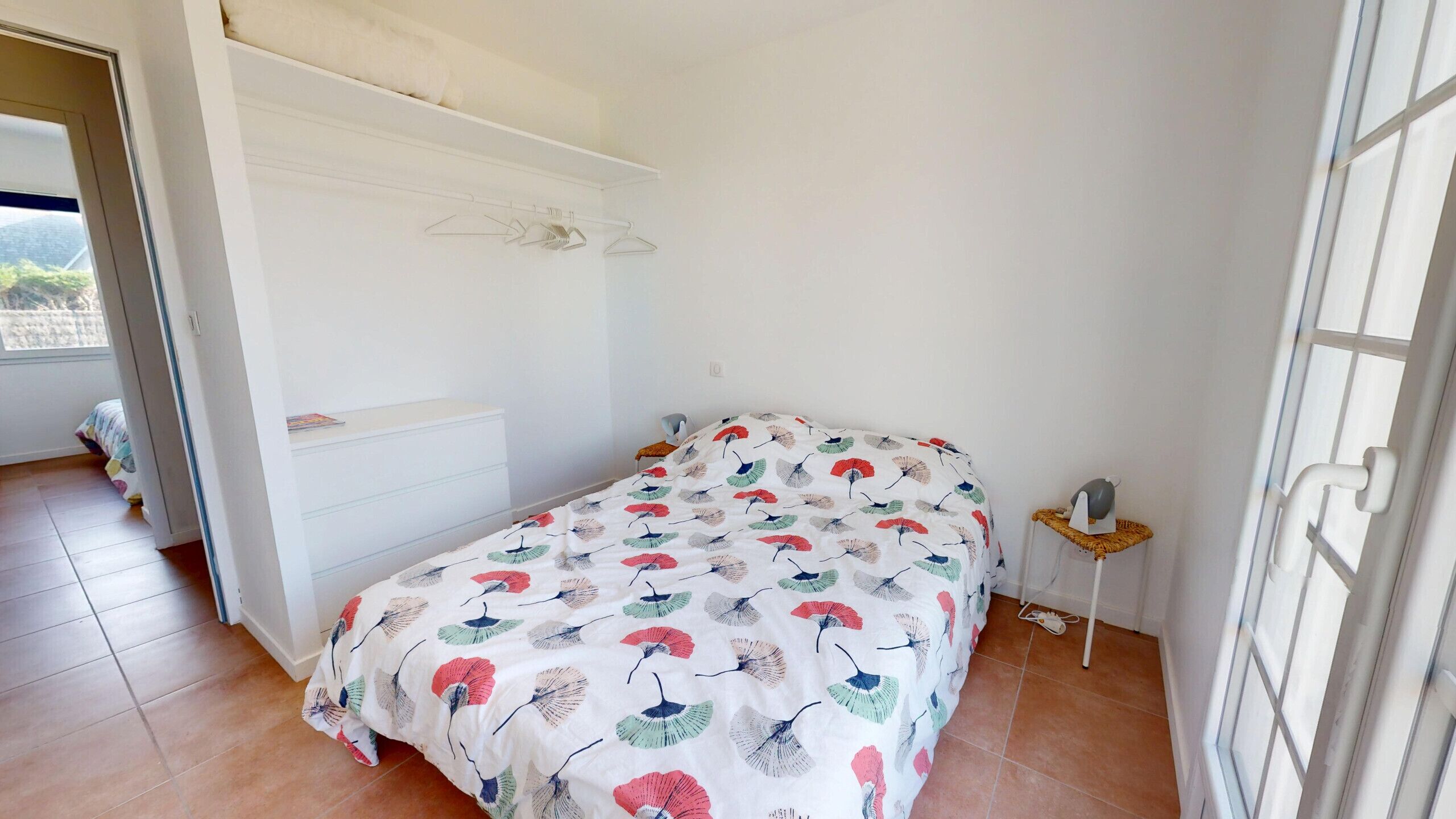 Un dormitorio con una cama, un aparador y una mesita de noche con una lámpara.