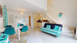A compact living space with a dining area, kitchenette, and a staircase. - Escale Bleu - House with Heated Pool (Notre-Dame-de-Monts)