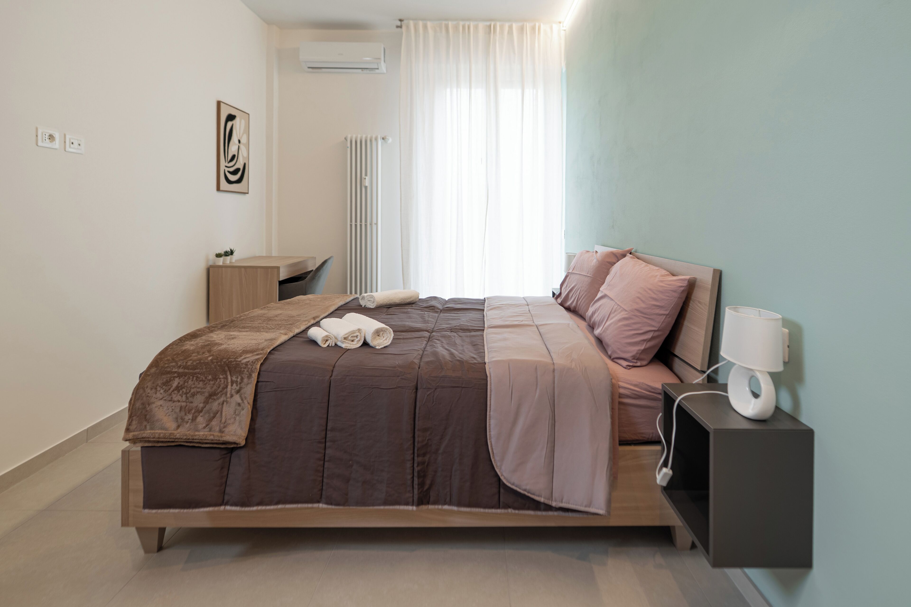 A modern bedroom with a bed, bedside table, and a wall-mounted lamp.