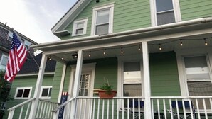 A green house with a porch, an American flag, and a welcome sign. - Littleton: Walk to Downtown, Adventure All Year (Littleton)