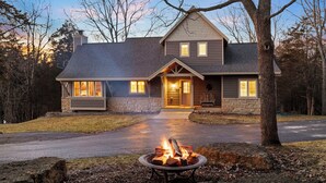 A two-story house with a stone foundation, a fireplace in the front yard, and a well-maintained lawn. - North Woods Lodge Vibes•Hot Tub+Fire Pit•3 Seasons Room•Galena Territory Retreat (Galena)