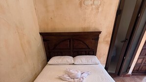 Ein Einzelbett mit Holz Kopfteil, weißer Bettdecke und zwei Kissen.