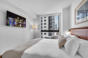 Ein Hotelzimmer mit großem Bett, Stadtblick, Flachbildfernseher und Fenster mit Blick auf Hochhäuser.