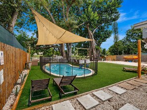 A backyard with a swimming pool, two lounge chairs, a wooden fence, and a large tree. - World Cup Lakefront Escape |Pool, Kayaks Sleeps 10 (Hollywood)