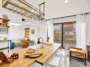 A modern kitchen with a wooden countertop, a sink, and a dining area with chairs and a table. - World Cup Lakefront Escape |Pool, Kayaks Sleeps 10 (Hollywood)